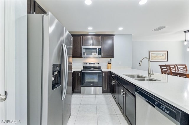 kitchen with light tile patterned flooring, sink, decorative light fixtures, dark brown cabinets, and stainless steel appliances