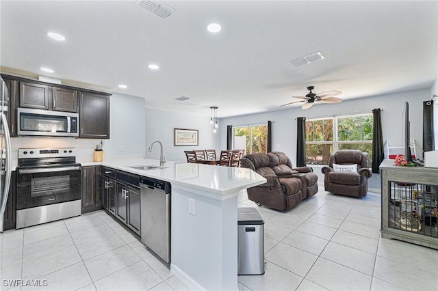 kitchen with appliances with stainless steel finishes, kitchen peninsula, sink, and light tile patterned floors