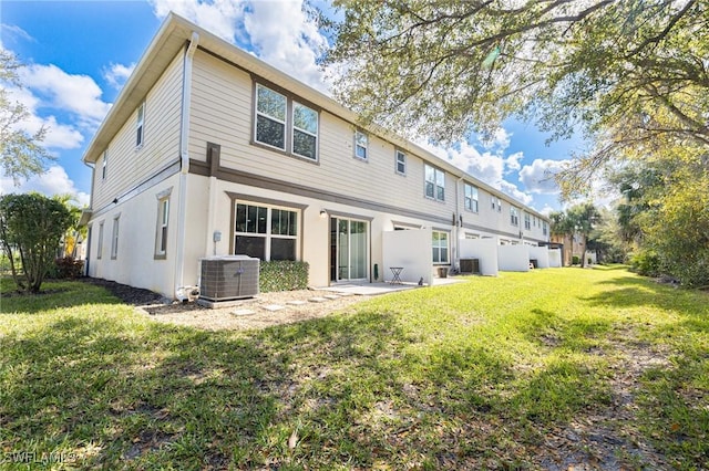 rear view of house with central AC, a patio, and a lawn