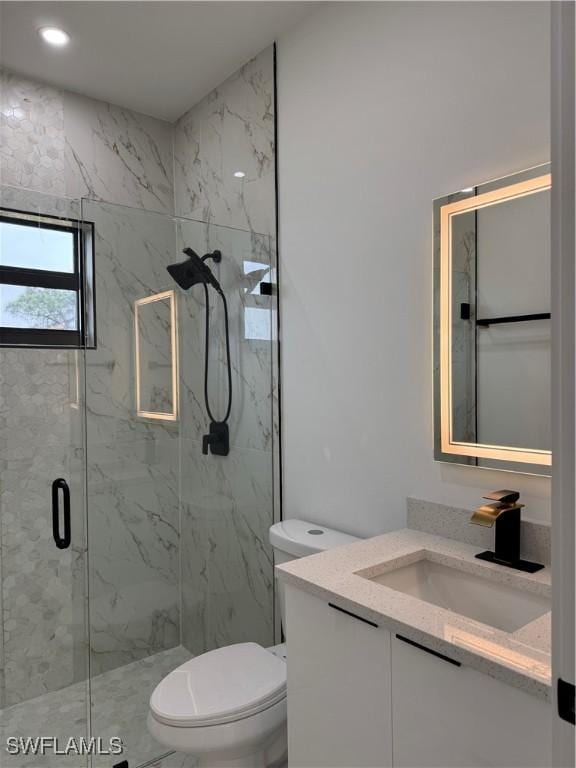 bathroom with vanity, a shower with shower door, and toilet