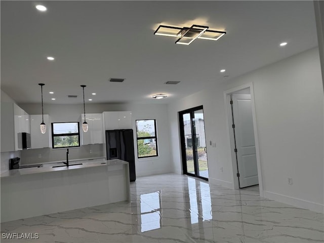 kitchen with electric stove, sink, white cabinets, black fridge with ice dispenser, and decorative light fixtures