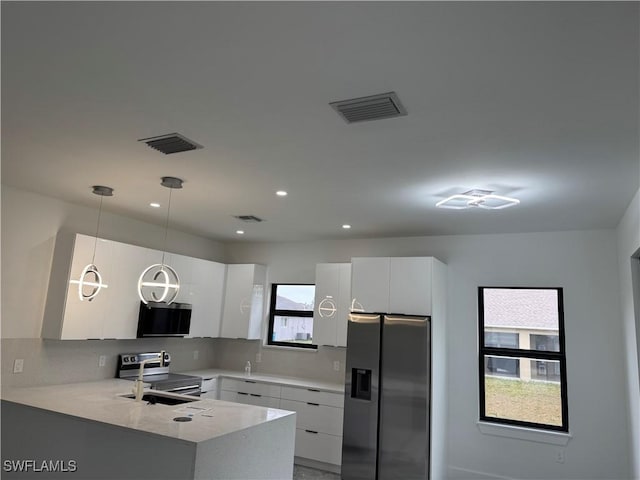 kitchen with appliances with stainless steel finishes, pendant lighting, and white cabinets