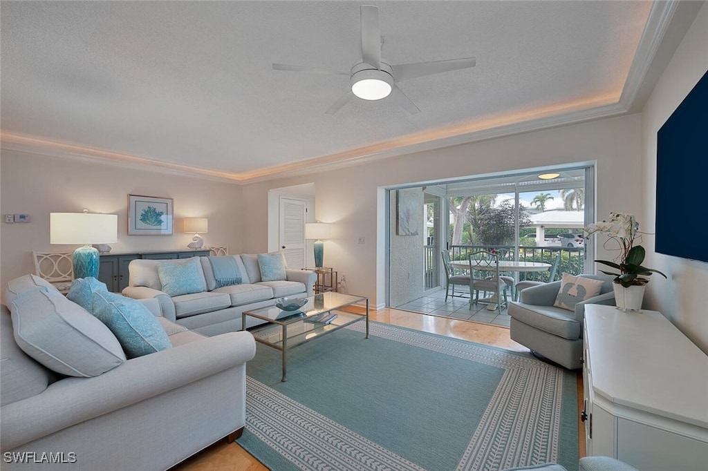 living room featuring ceiling fan, ornamental molding, light tile patterned floors, and a textured ceiling