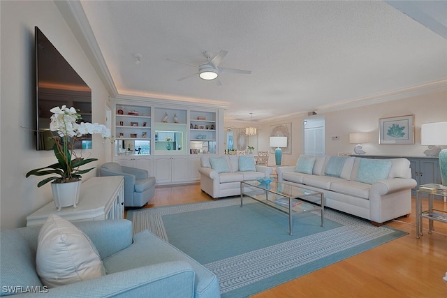 living room with built in features, light wood-type flooring, crown molding, and a textured ceiling