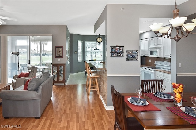 dining space with a notable chandelier, baseboards, and light wood-style floors