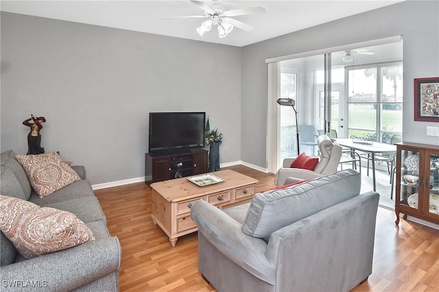 living area featuring light wood-style flooring, baseboards, and a ceiling fan