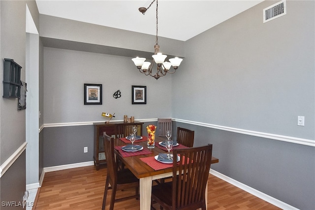 dining area featuring an inviting chandelier, wood finished floors, visible vents, and baseboards