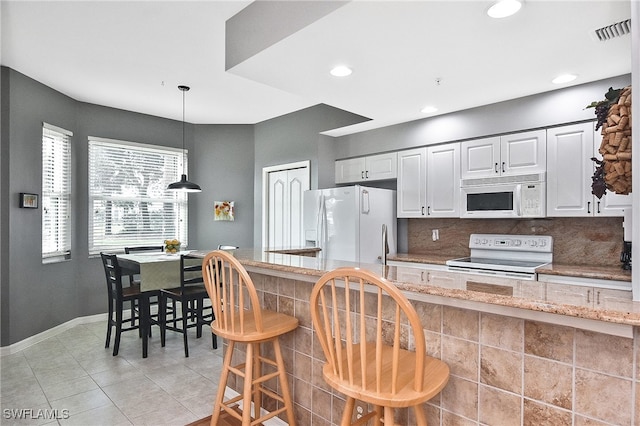 kitchen featuring pendant lighting, white appliances, light stone countertops, and white cabinetry