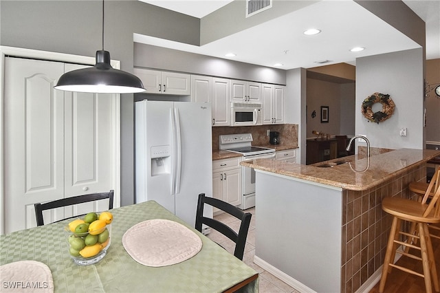 kitchen with white appliances, sink, hanging light fixtures, and white cabinets