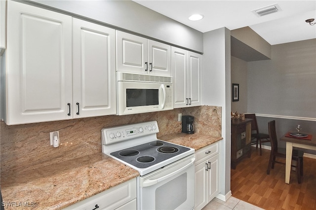 kitchen with light stone counters, visible vents, decorative backsplash, white cabinets, and white appliances