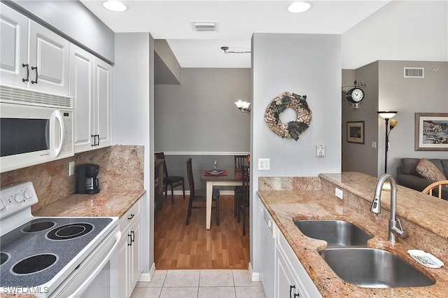 kitchen with white appliances, visible vents, light stone counters, and a sink