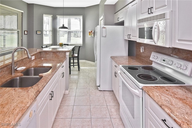 kitchen with light tile patterned flooring, white appliances, a sink, white cabinetry, and decorative light fixtures