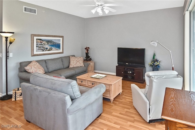 living area with light wood-style floors, ceiling fan, visible vents, and baseboards