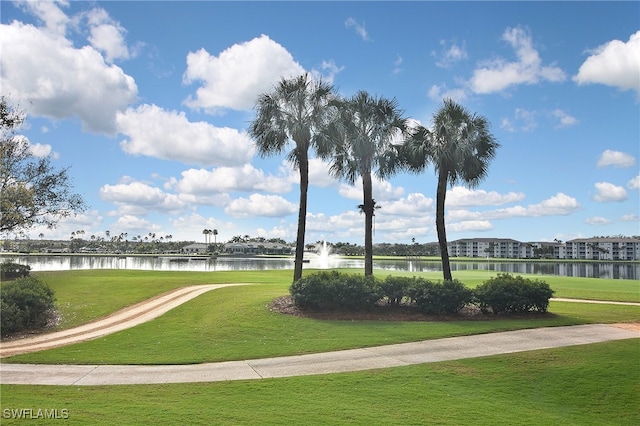 surrounding community with a water view and a lawn