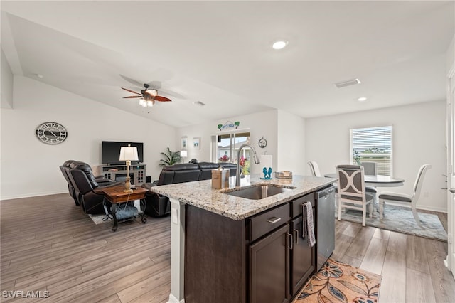 kitchen with sink, light hardwood / wood-style flooring, dark brown cabinets, an island with sink, and stainless steel dishwasher