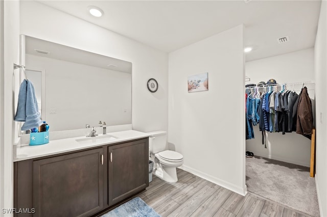 bathroom with hardwood / wood-style flooring, vanity, and toilet