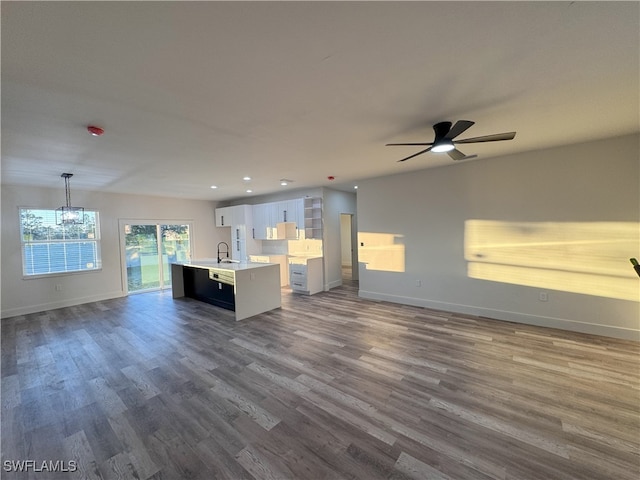 kitchen featuring decorative light fixtures, dark wood-type flooring, a kitchen island with sink, and white cabinets