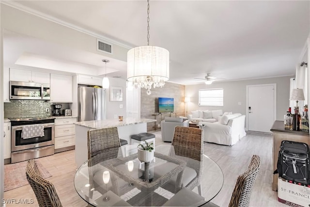 dining room featuring crown molding, light hardwood / wood-style flooring, and ceiling fan with notable chandelier