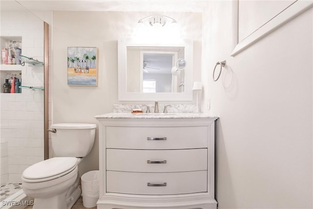 bathroom featuring vanity, a tile shower, and toilet