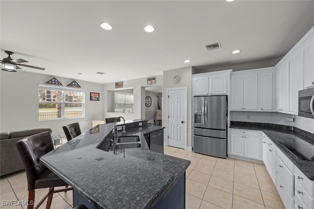 kitchen with black appliances, white cabinetry, light tile patterned floors, sink, and an island with sink