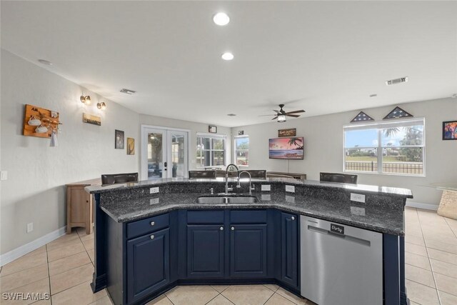 kitchen with stainless steel dishwasher, sink, blue cabinetry, a kitchen island with sink, and light tile patterned floors