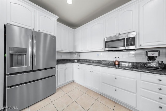 kitchen featuring white cabinetry, stainless steel appliances, and dark stone counters