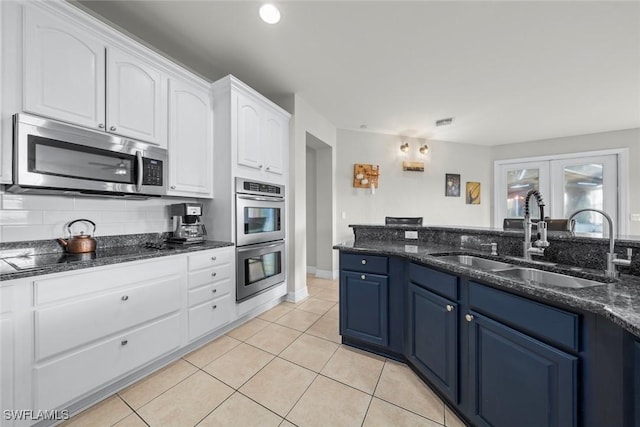 kitchen with white cabinetry, stainless steel appliances, sink, blue cabinetry, and light tile patterned flooring