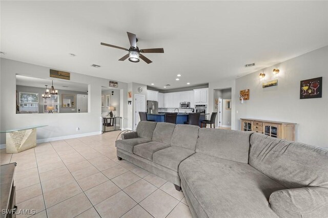 living room with light tile patterned flooring and ceiling fan with notable chandelier