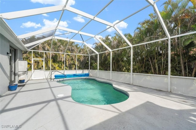 view of pool with glass enclosure and a patio area