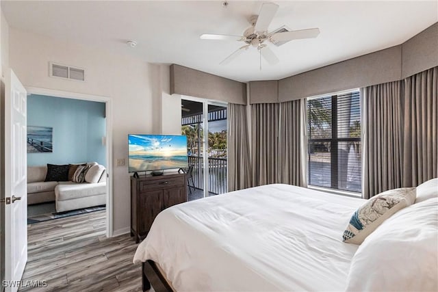 bedroom featuring access to exterior, ceiling fan, multiple windows, and hardwood / wood-style flooring