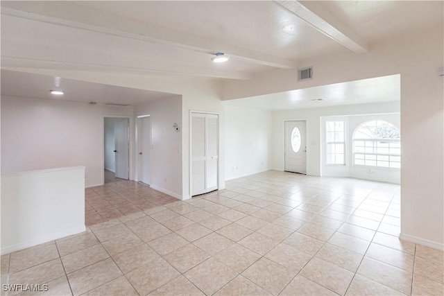 spare room with light tile patterned floors and beam ceiling