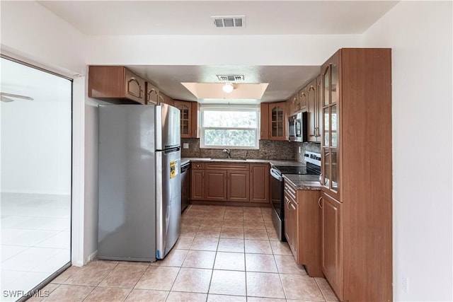 kitchen featuring tasteful backsplash, stainless steel appliances, light tile patterned flooring, and sink