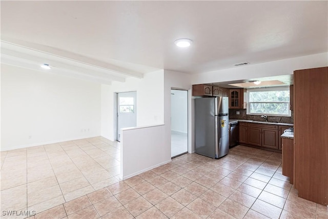 kitchen featuring tasteful backsplash, black dishwasher, sink, stainless steel fridge, and light tile patterned floors