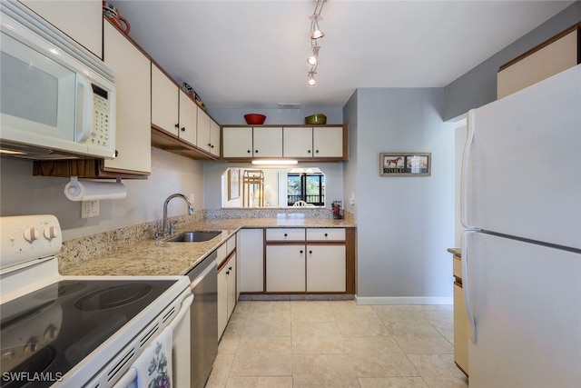 kitchen with white appliances, sink, rail lighting, kitchen peninsula, and light tile patterned floors