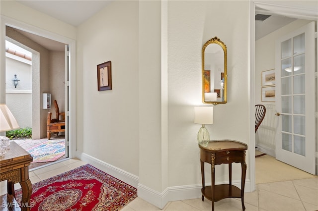 hall featuring tile patterned flooring, french doors, visible vents, and baseboards