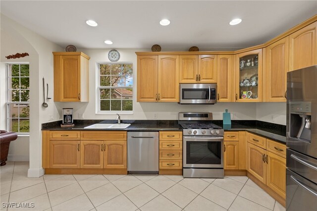 kitchen with appliances with stainless steel finishes, sink, and dark stone countertops