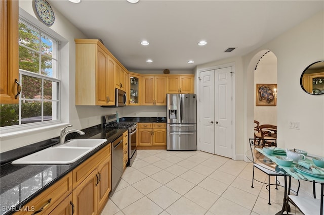 kitchen featuring arched walkways, glass insert cabinets, appliances with stainless steel finishes, a sink, and recessed lighting