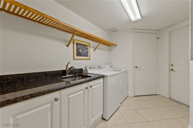 clothes washing area with sink, light tile patterned floors, independent washer and dryer, and a textured ceiling