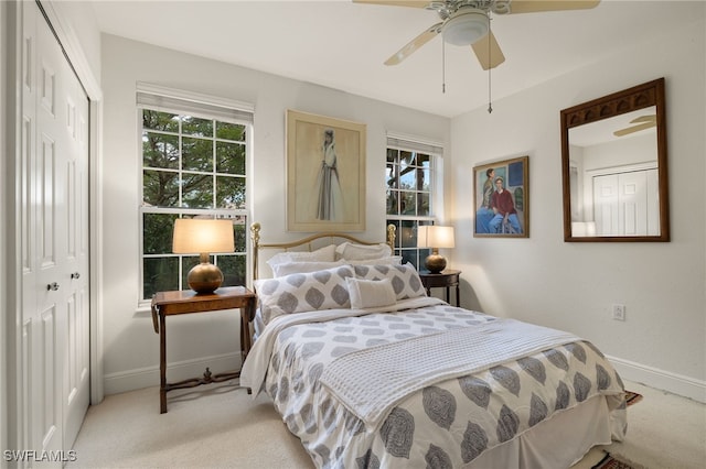 bedroom featuring a closet, light colored carpet, ceiling fan, and baseboards