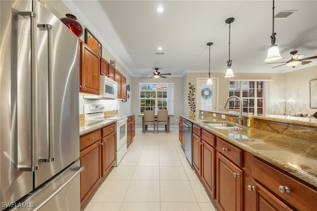 kitchen featuring appliances with stainless steel finishes, light stone countertops, pendant lighting, ornamental molding, and sink