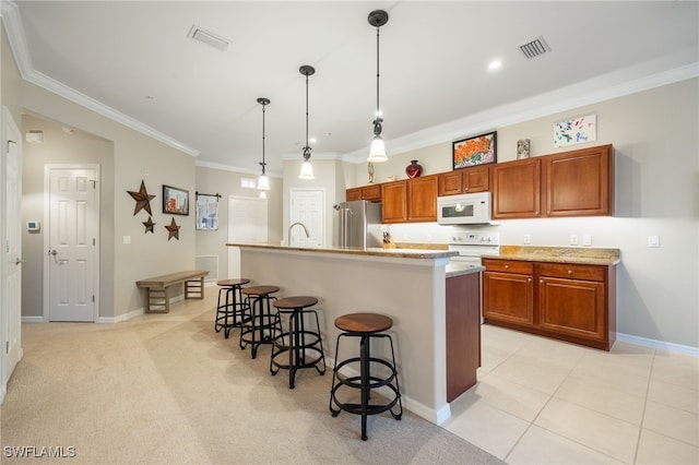 kitchen featuring white appliances, pendant lighting, a kitchen breakfast bar, crown molding, and an island with sink