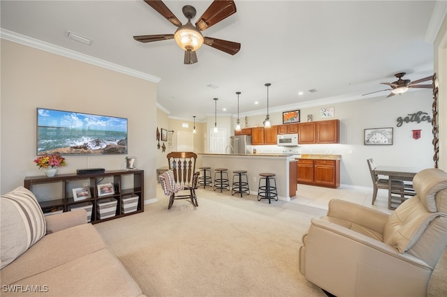 living room with ceiling fan, ornamental molding, and light colored carpet