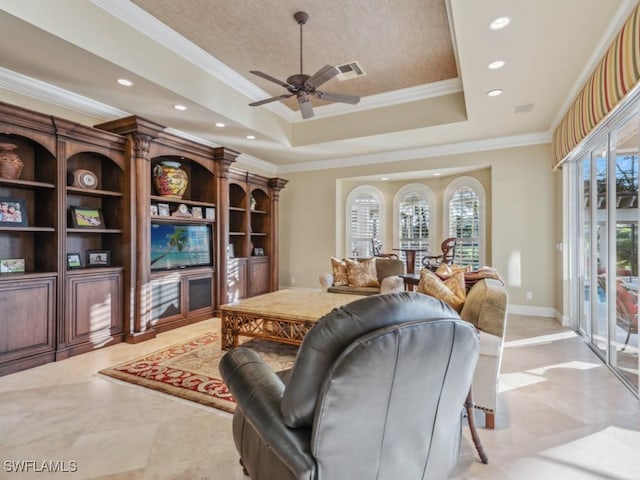 living room featuring ceiling fan, a tray ceiling, ornamental molding, and a healthy amount of sunlight