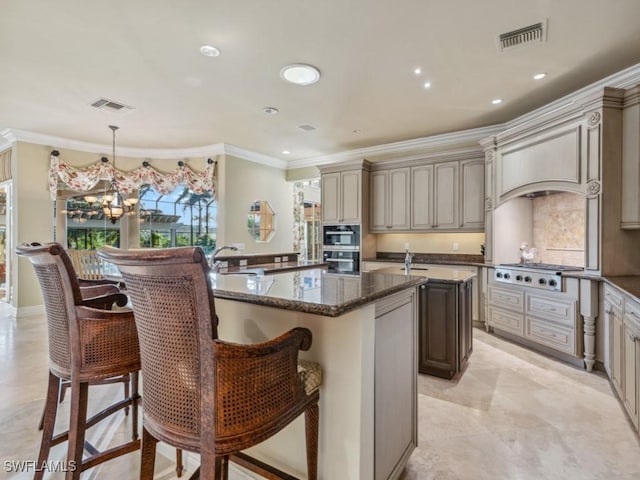 kitchen featuring stainless steel gas stovetop, dark stone countertops, hanging light fixtures, a center island, and crown molding