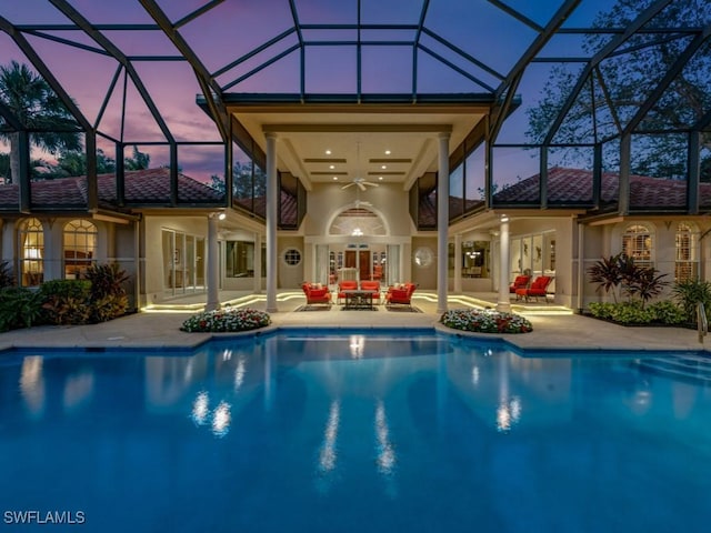 pool at dusk featuring an outdoor living space, a lanai, a patio, and ceiling fan