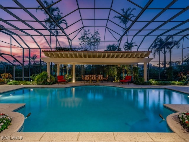 pool at dusk with a patio area and glass enclosure