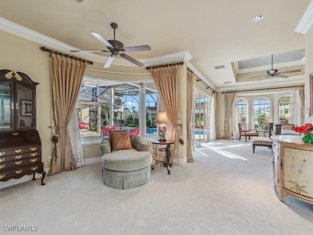 living area with a raised ceiling, crown molding, light colored carpet, and ceiling fan