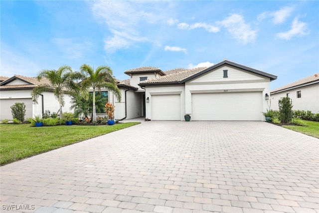 view of front of property featuring a garage, a tile roof, decorative driveway, stucco siding, and a front yard