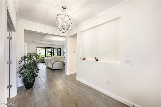 hallway featuring hardwood / wood-style floors, crown molding, and a notable chandelier