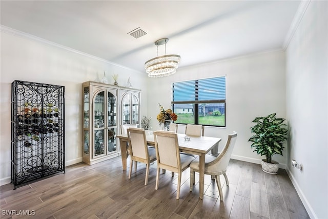 dining room featuring crown molding, hardwood / wood-style flooring, and a chandelier